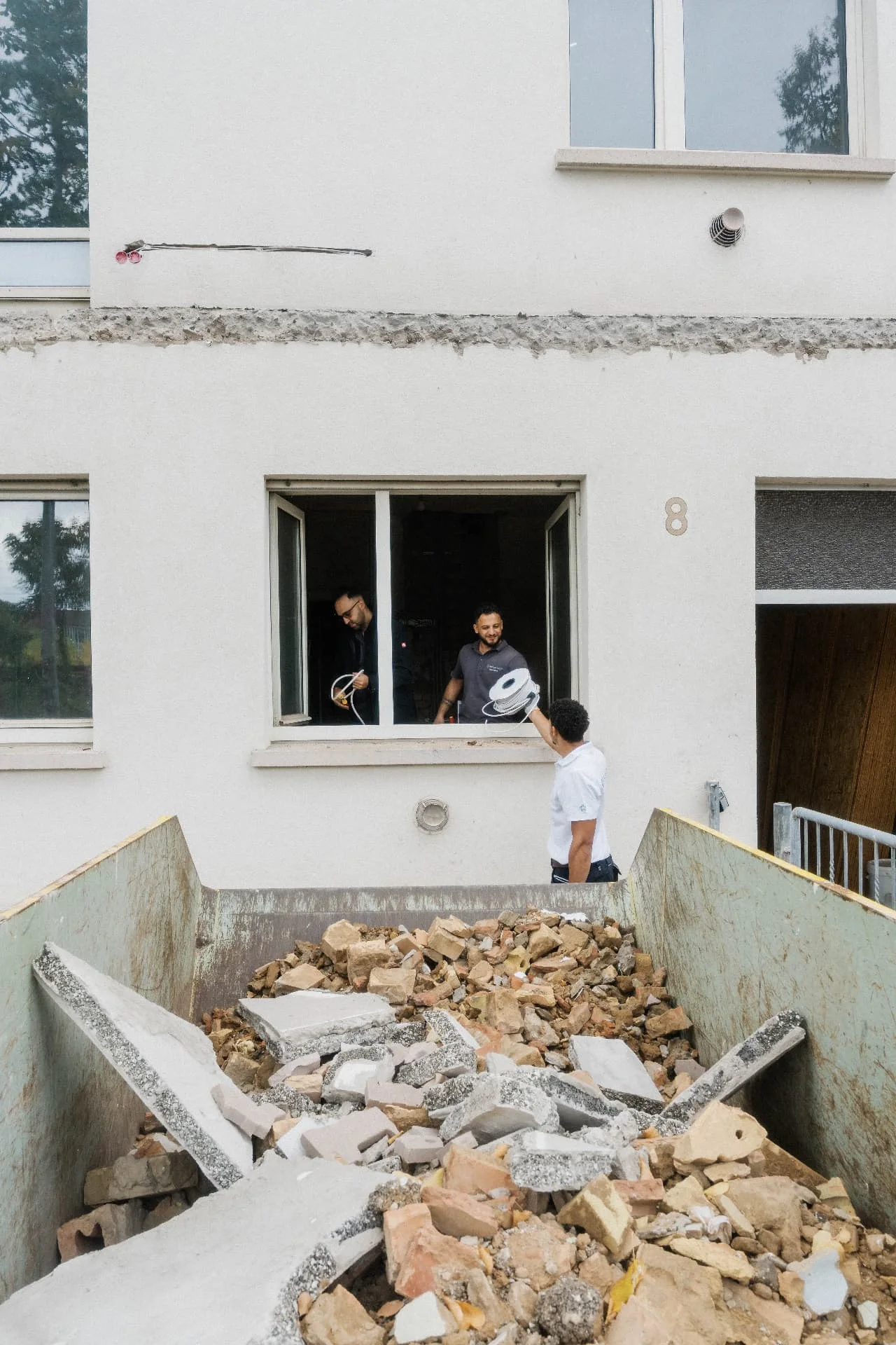 HausEtage-Team bei der Materialübergabe durch ein Fenster am Rebstock 8 in Mannheim