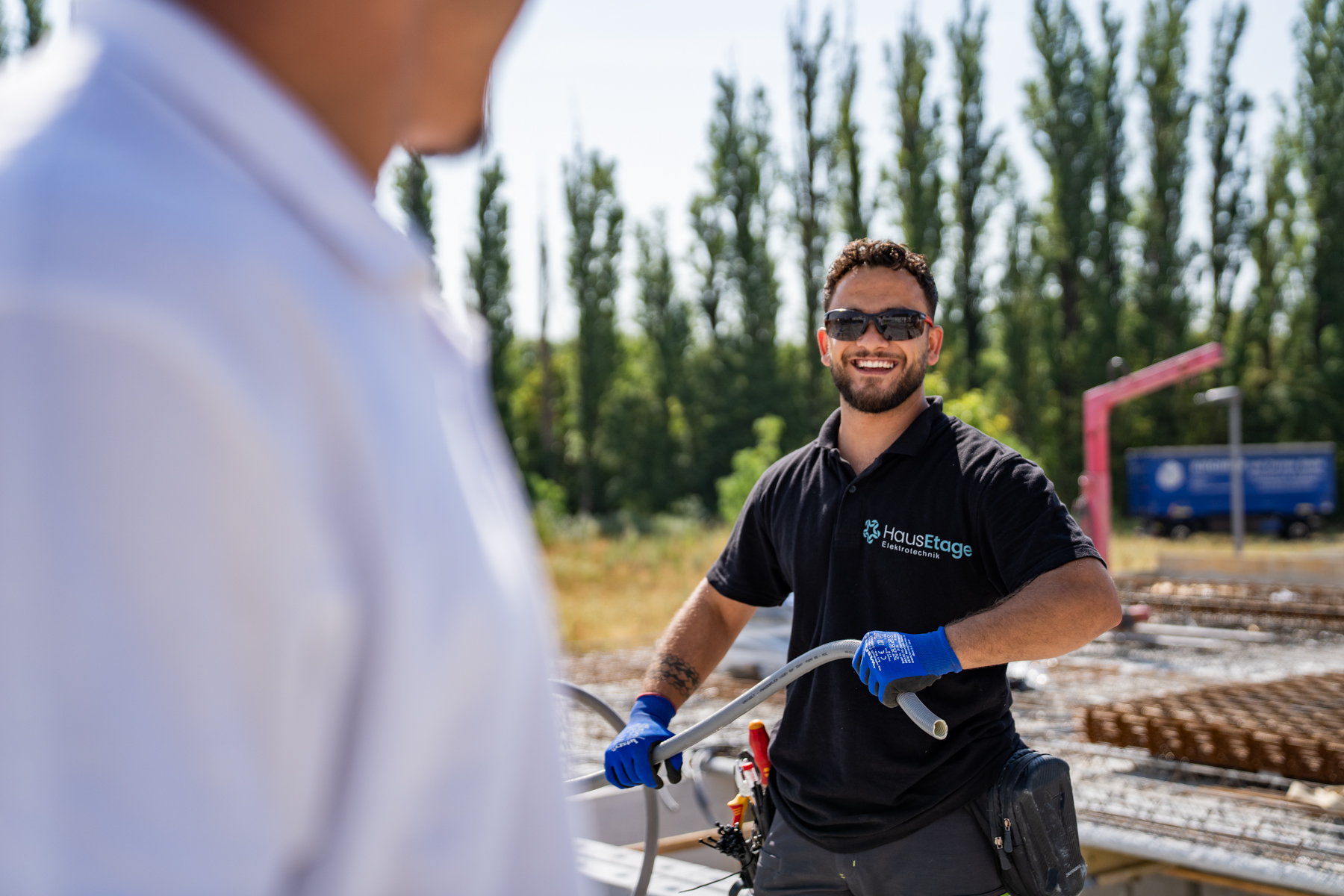 Elektriker von HausEtage zieht Leerrohr auf der Baustelle und lacht in die Kamera